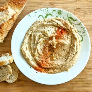 Light hummus on a plate with paprika parsley, and garlic