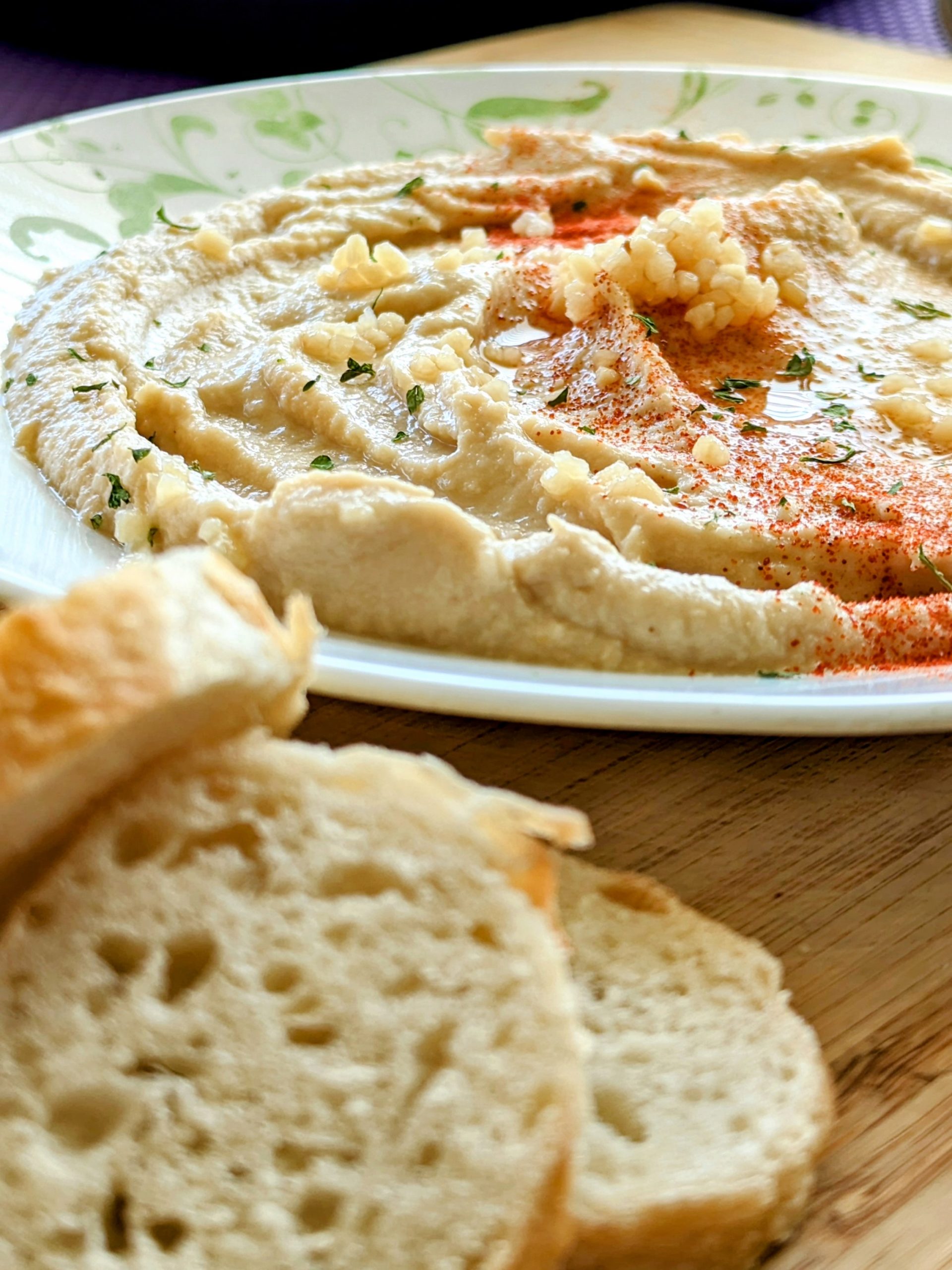 Light hummus on a plate near baguette slices for dipping