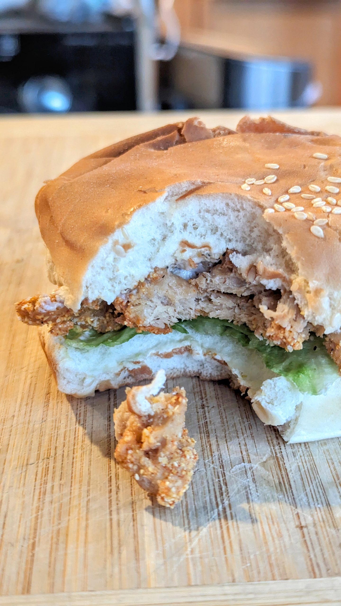 Plant-Based McChicken Sandwich with a bite taken out of it on a cutting board